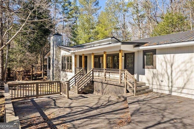 view of front facade featuring stairs, a deck, a chimney, and metal roof