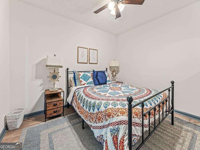 bedroom with a textured ceiling, ceiling fan, wood finished floors, and baseboards