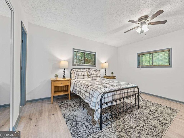 bedroom with multiple windows, wood finished floors, and baseboards