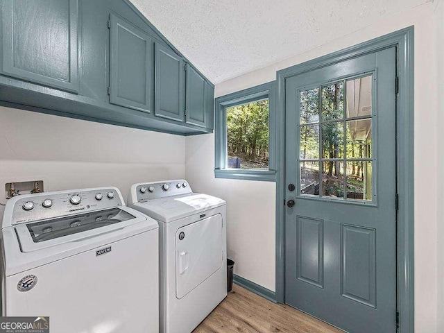 washroom with washing machine and clothes dryer, cabinet space, light wood-style floors, a textured ceiling, and baseboards