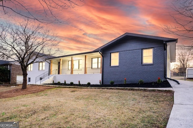 view of front facade featuring a front yard, a porch, and brick siding