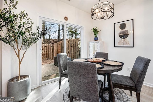 dining room with light wood-type flooring, an inviting chandelier, and baseboards