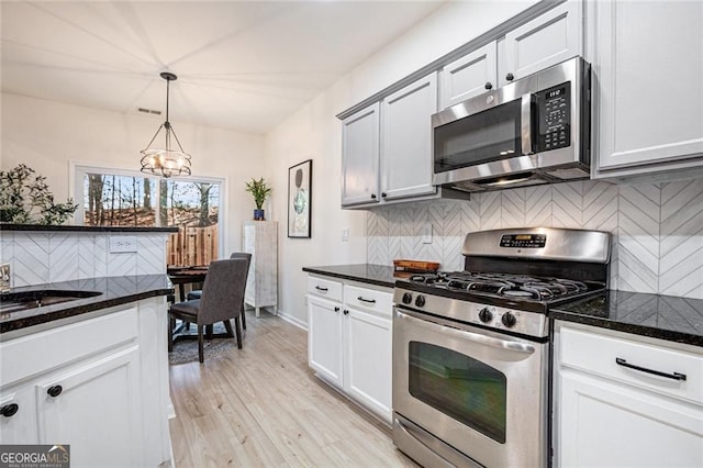 kitchen featuring stainless steel appliances, pendant lighting, white cabinets, and light wood finished floors