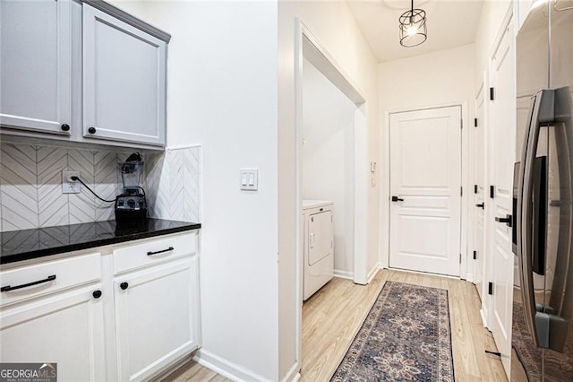 kitchen with light wood-style flooring, white cabinets, freestanding refrigerator, washing machine and clothes dryer, and decorative light fixtures