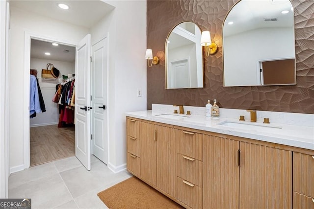 bathroom featuring double vanity, a spacious closet, visible vents, and a sink