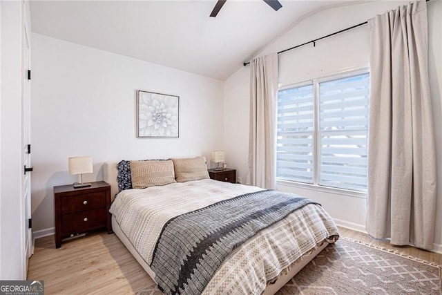 bedroom featuring light wood-type flooring, baseboards, a ceiling fan, and lofted ceiling