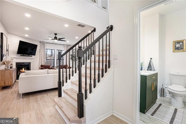 interior space featuring recessed lighting, visible vents, a lit fireplace, and wood finished floors