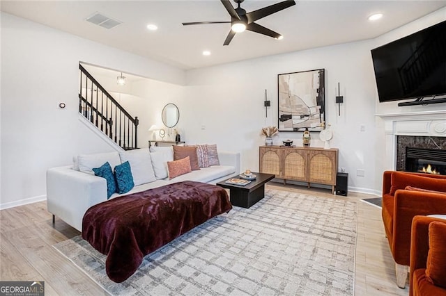 living room featuring light wood finished floors, recessed lighting, visible vents, and a high end fireplace