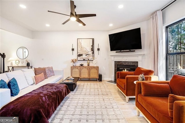 living area with a ceiling fan, recessed lighting, light wood-style flooring, and a premium fireplace