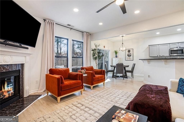 living room with visible vents, baseboards, a high end fireplace, and light wood-style floors