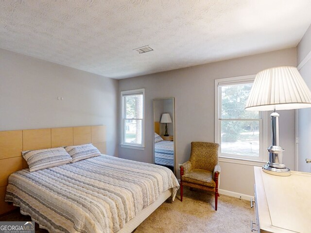 bedroom featuring baseboards, carpet, visible vents, and a textured ceiling