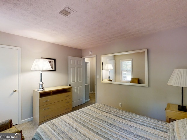 bedroom featuring a textured ceiling, visible vents, and light colored carpet