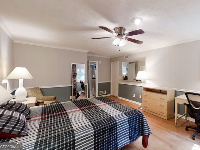 bedroom featuring visible vents, a ceiling fan, light wood-style flooring, ornamental molding, and a textured ceiling