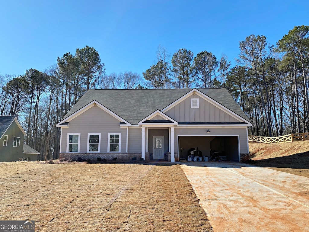 view of front of home with driveway, an attached garage, board and batten siding, and brick siding