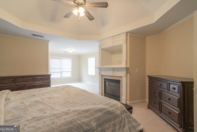 bedroom with a tray ceiling, visible vents, and light carpet