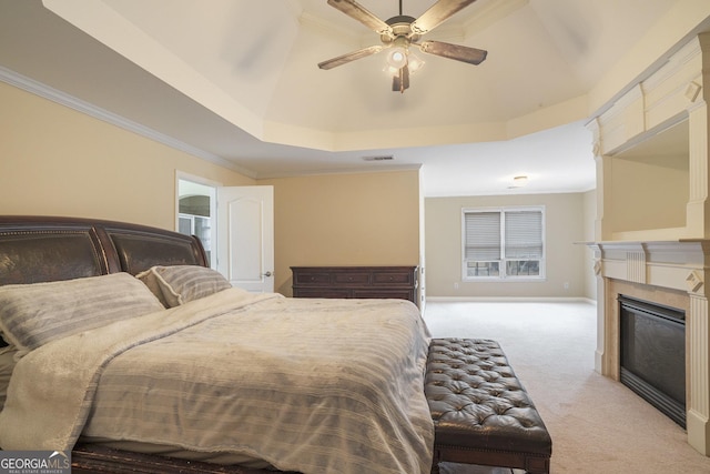 bedroom with a raised ceiling, light colored carpet, visible vents, a glass covered fireplace, and baseboards