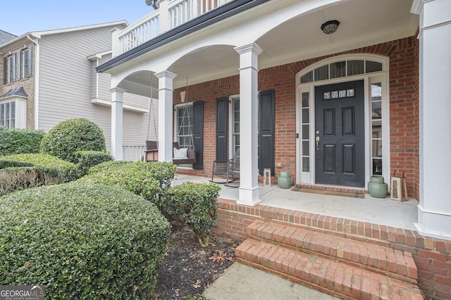 doorway to property with a porch and brick siding