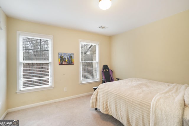 bedroom featuring visible vents, light carpet, and baseboards