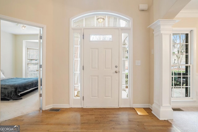 entrance foyer with visible vents, light wood-style flooring, decorative columns, and baseboards