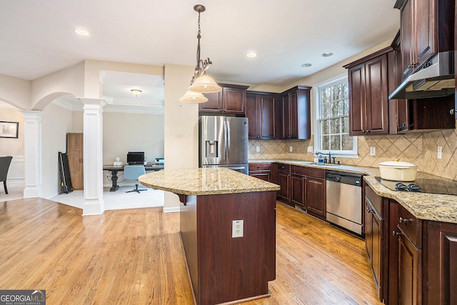 kitchen with arched walkways, appliances with stainless steel finishes, a center island, decorative light fixtures, and ornate columns