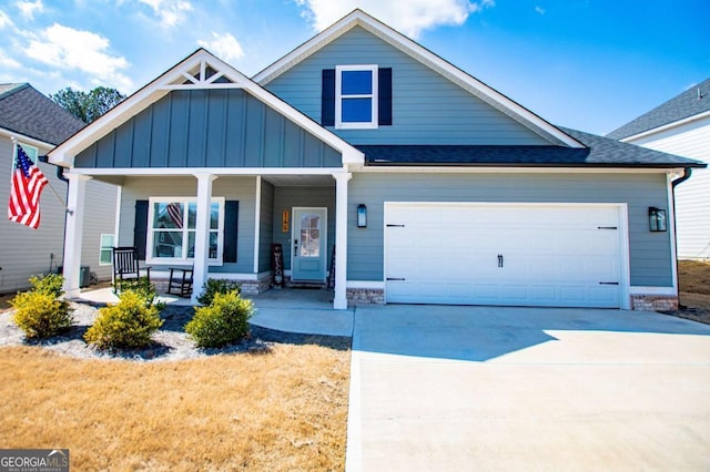 view of front of property with driveway, a shingled roof, an attached garage, covered porch, and board and batten siding