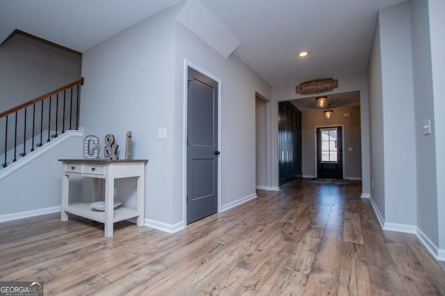 foyer entrance featuring wood finished floors, stairway, baseboards, and recessed lighting