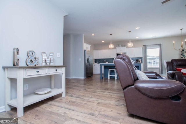 living room featuring light wood finished floors, recessed lighting, a chandelier, and baseboards
