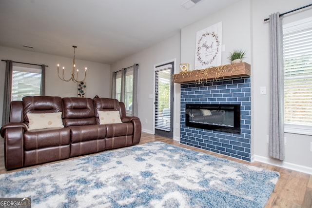 living room with a chandelier, wood finished floors, a tiled fireplace, and baseboards