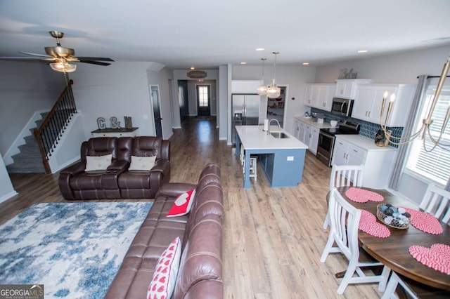 living area featuring light wood-style flooring, plenty of natural light, stairway, ceiling fan, and recessed lighting