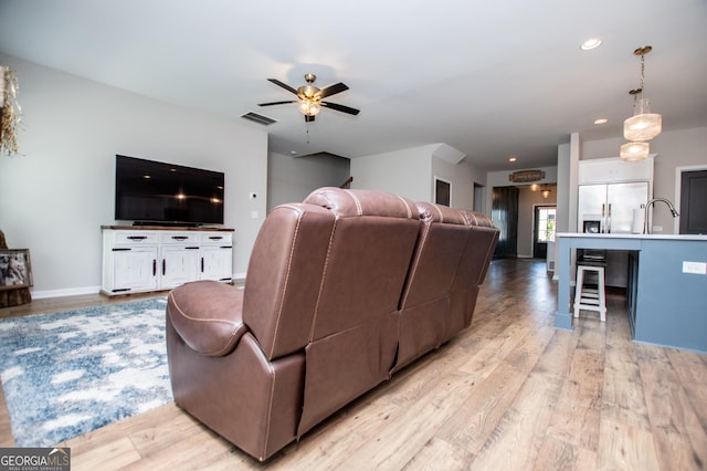 living area featuring light wood-type flooring, a ceiling fan, recessed lighting, and baseboards
