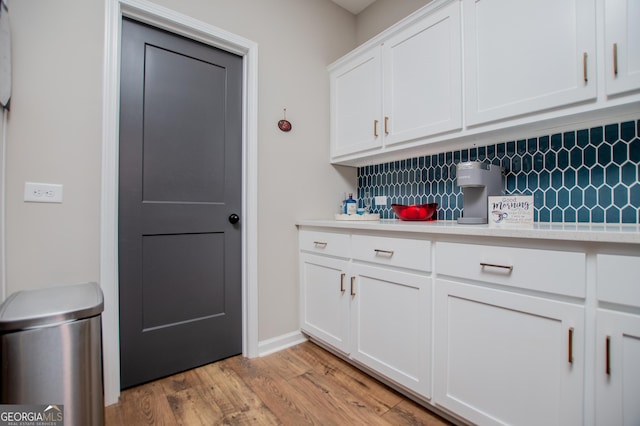 bar area with decorative backsplash, light wood finished floors, and baseboards