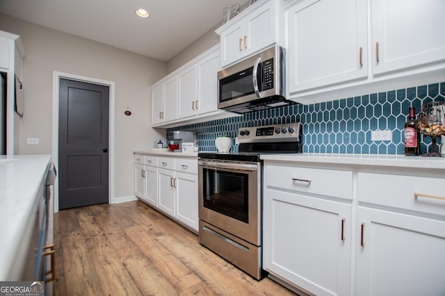 kitchen featuring stainless steel appliances, light countertops, backsplash, light wood-style flooring, and recessed lighting