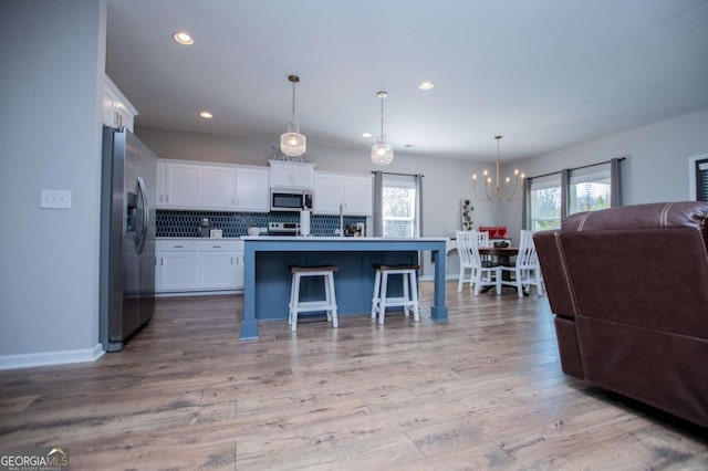 kitchen featuring appliances with stainless steel finishes, open floor plan, a chandelier, white cabinets, and tasteful backsplash
