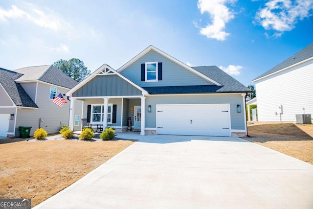 view of front of house featuring board and batten siding, covered porch, central air condition unit, concrete driveway, and a front yard