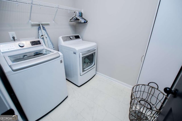 washroom featuring independent washer and dryer, light marble finish flooring, and baseboards