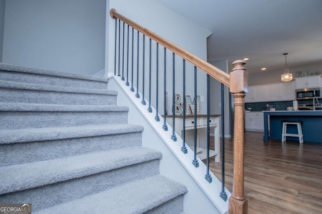 staircase featuring wood finished floors and recessed lighting
