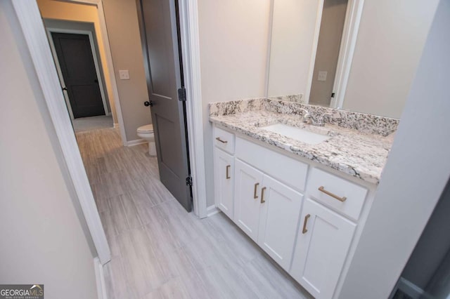 bathroom with toilet, vanity, and baseboards