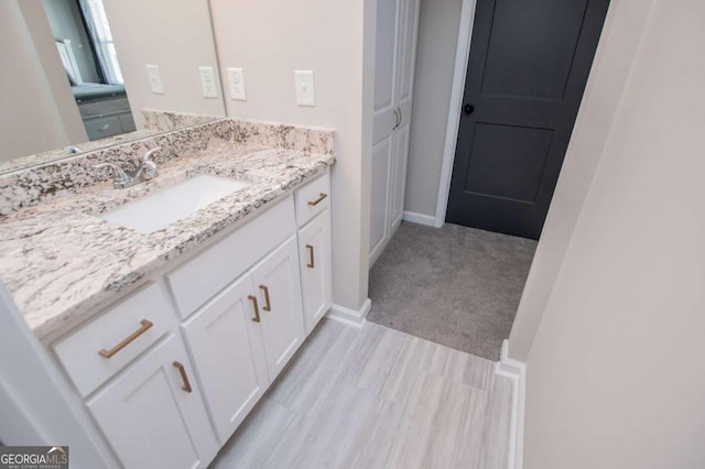 bathroom featuring vanity, baseboards, and wood finished floors