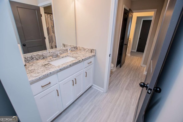 bathroom with baseboards, toilet, vanity, and wood finished floors