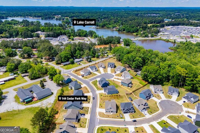aerial perspective of suburban area with a nearby body of water and a forest