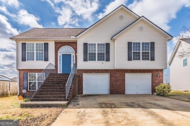 raised ranch with driveway, brick siding, and an attached garage