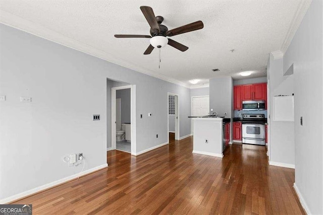 kitchen featuring dark wood-style floors, crown molding, dark countertops, appliances with stainless steel finishes, and baseboards