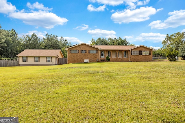 single story home featuring brick siding, fence, and a front yard