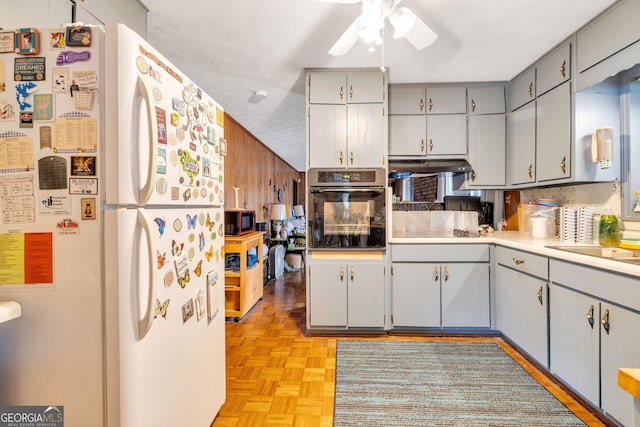 kitchen featuring ceiling fan, under cabinet range hood, light countertops, gray cabinetry, and black appliances