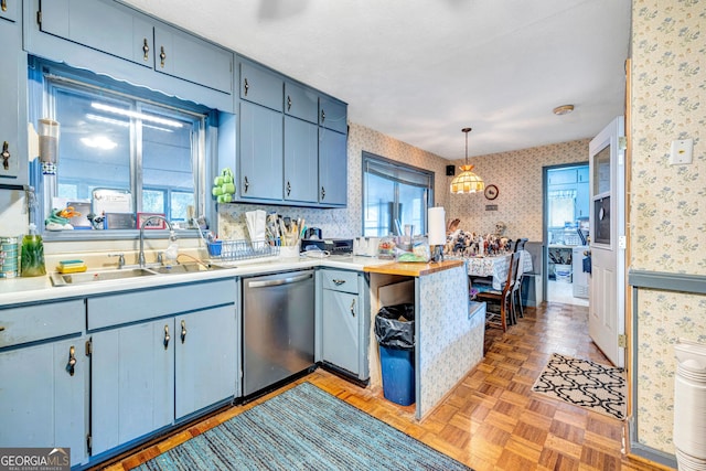 kitchen featuring wallpapered walls, pendant lighting, light countertops, and stainless steel dishwasher