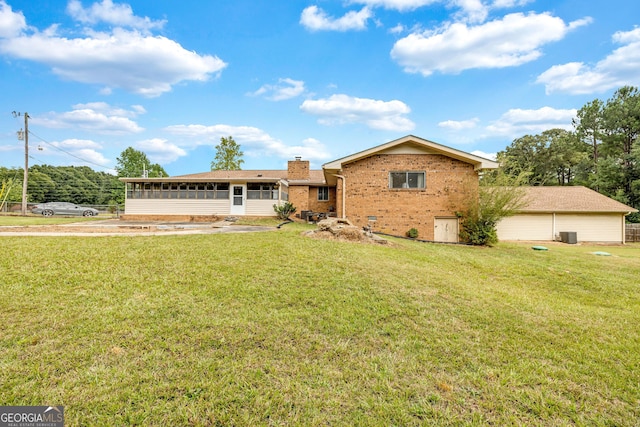 single story home with a sunroom, a chimney, a front lawn, and brick siding