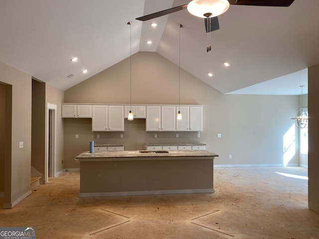 kitchen with light stone counters, a ceiling fan, a kitchen island with sink, white cabinets, and high vaulted ceiling