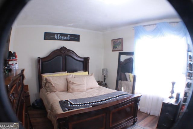 bedroom with ornamental molding and wood finished floors