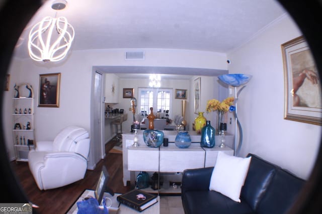 living room with crown molding, visible vents, and a notable chandelier