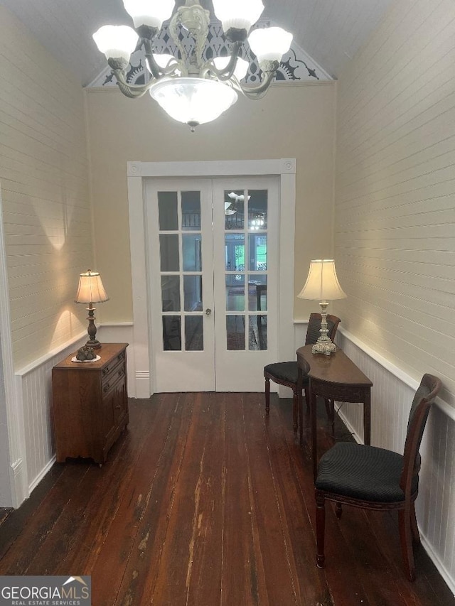 sitting room with french doors, dark wood-type flooring, wainscoting, and a notable chandelier